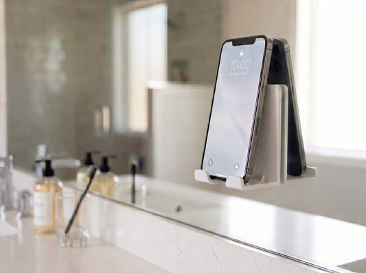 AIRSTIK white nano-suction phone cradle on a bathroom mirror holding a phone hands-free