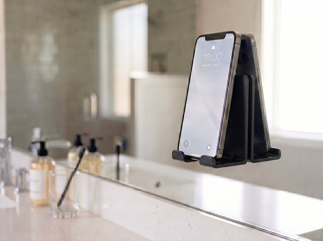 AIRSTIK black nano-suction phone cradle on a bathroom mirror holding a phone hands-free